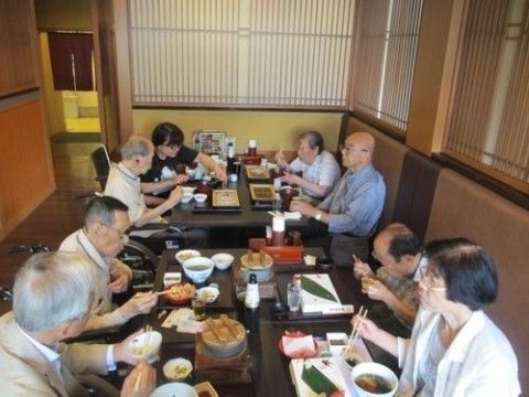 外出先にて、座敷に座って各々食事をとっている入居者たち