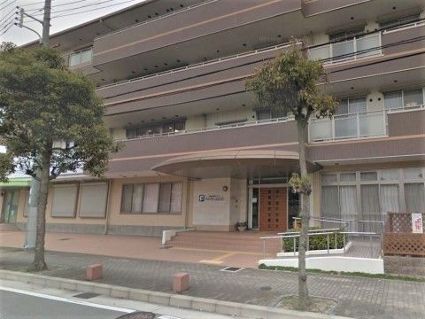 建物前に木が二本立ち、玄関前にスロープが付いている施設の外観