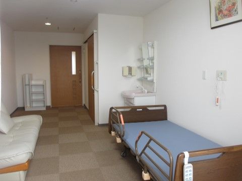 手すり付きで青いマットが置かれているベッドが設置された居室