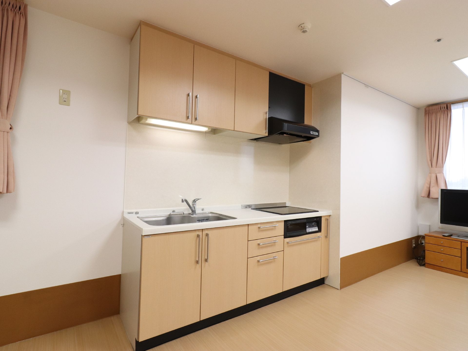 キッチンの上下には調味料や調理器具などを収納できる場所があり、流し台の横には調理スペースとIHコンロが備えられている。