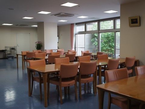 ブルーの床とオレンジの椅子が鮮やかな、リビング兼食堂は、入居者様が楽しんでお食事いただける場所になっている。