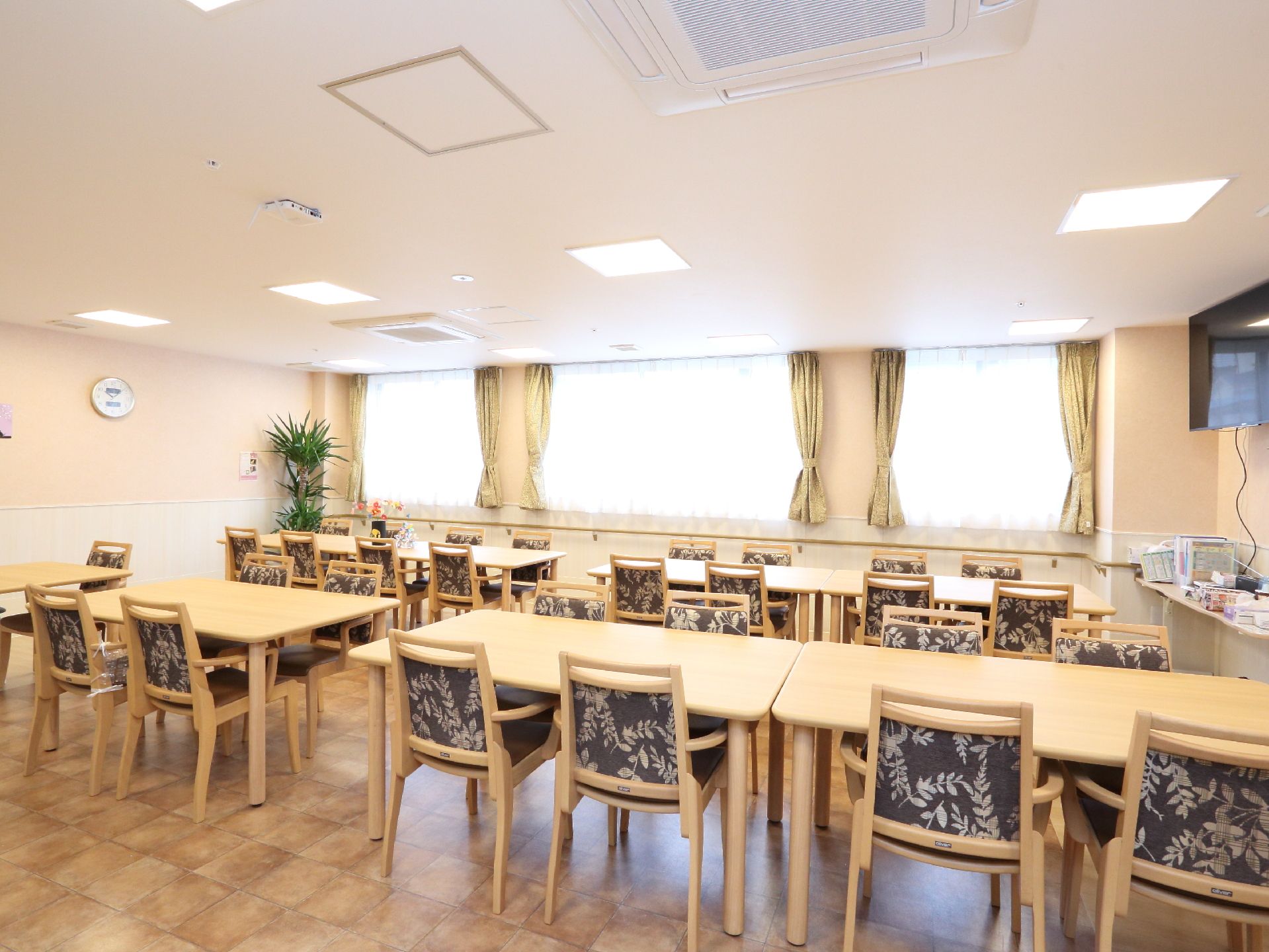 食堂として食事を楽しんだり、デイサービスとしてレクリエーションをすることもできるスペースである。窓があり明るい空間である。