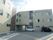 施設の建物は、L字型をしていて、右上に大きく施設名が表示されている。壁はベージュ色で、こげ茶色の線が縦に入っている場所もある。
