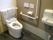 トイレ内には手すりが２か所に設置され、便器前のものには背もたれがついている。壁には緊急呼び出しボタンがあり、洗面台が備えてある。