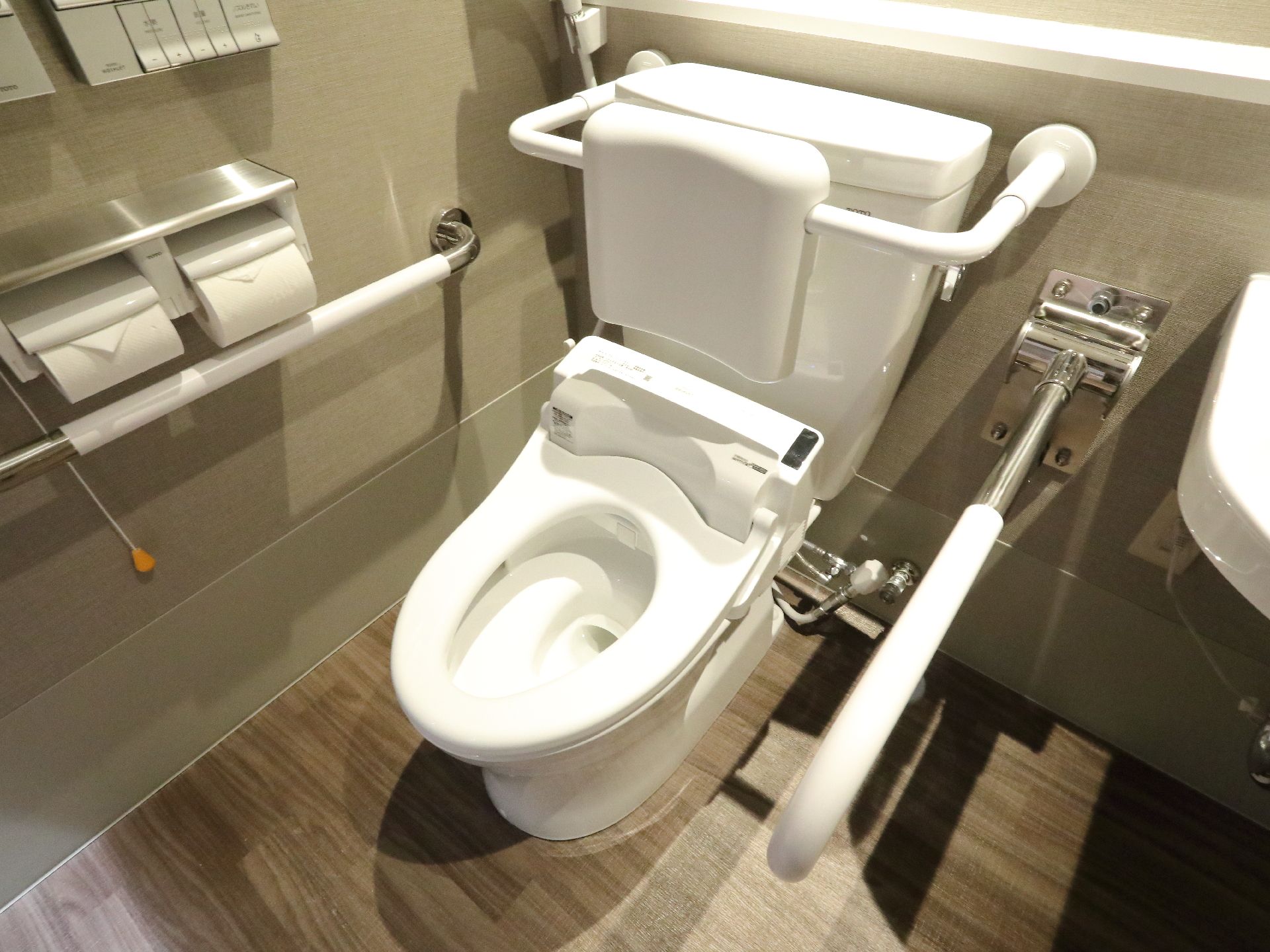 トイレの両脇には、手すりが設置されている。ウォッシュレットタイプのトイレで、壁にあるボタンで操作が可能。