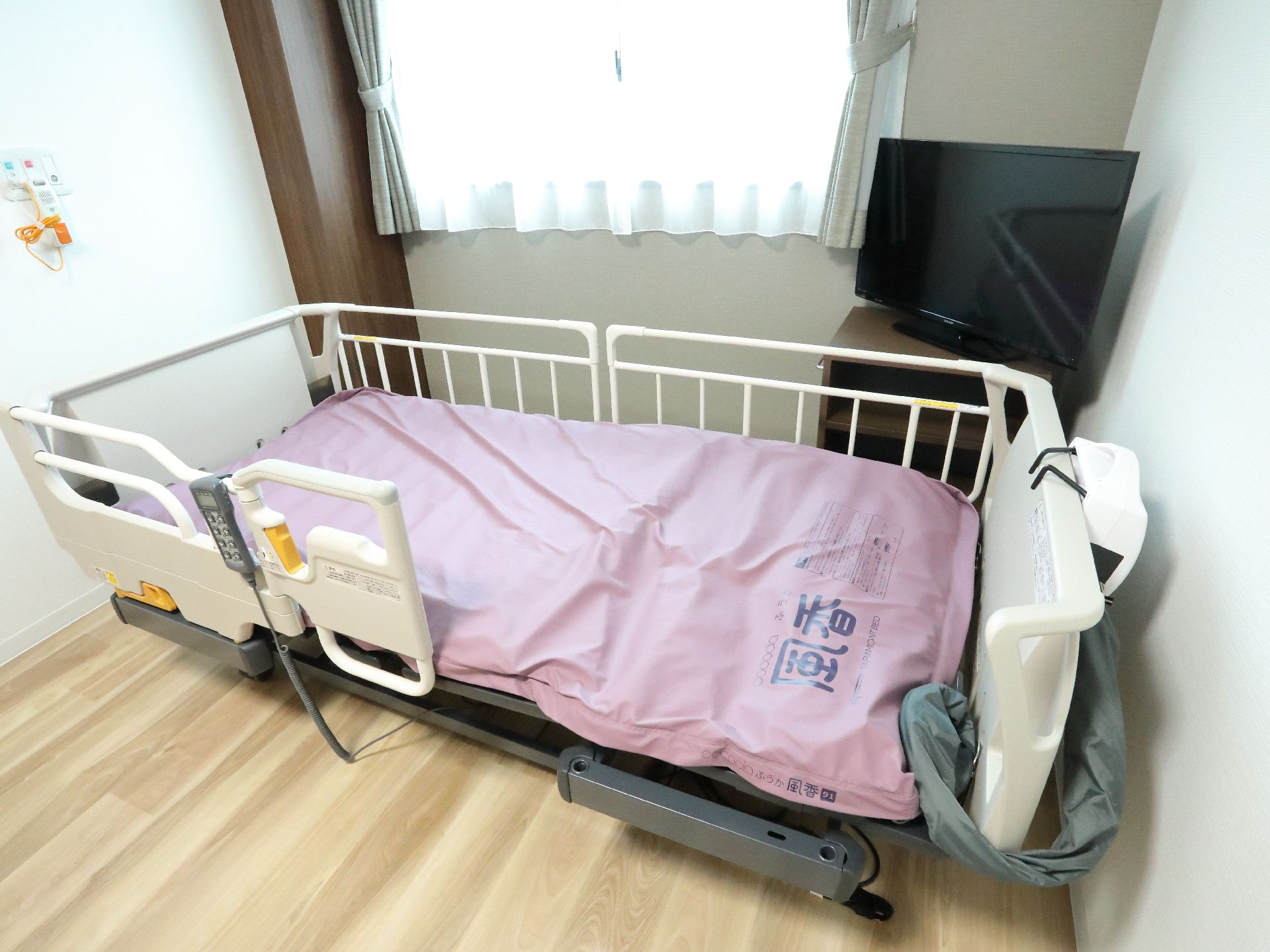 居室の奥にあるベッドの近くには、ナースコールが設置されている。紐も付いているので、横になったまま呼び出し可能。