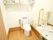 広さにゆとりのある明るいトイレには、洋式トイレ、洗面台、棚、複数の手すり、トイレットペーパーが設置されている。