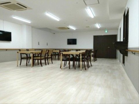 広々とした食堂。床はバリアフリーで入居者様も安心して移動できる。テーブルと椅子が十分な数が用意されている。
