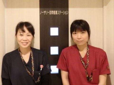 介護ステーションのドアの前に正面を向いて立つ施設の職員