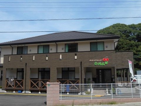 施設の建物の外観である。部屋の前にベランダが設けられる構造になっており、１階の玄関には階段のほか、スロープがつながっている。