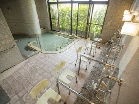 床と壁は石貼り、浴槽はタイル貼りで手すりを使って入る。大きな窓に面しており、入浴しながら庭の緑が見える。