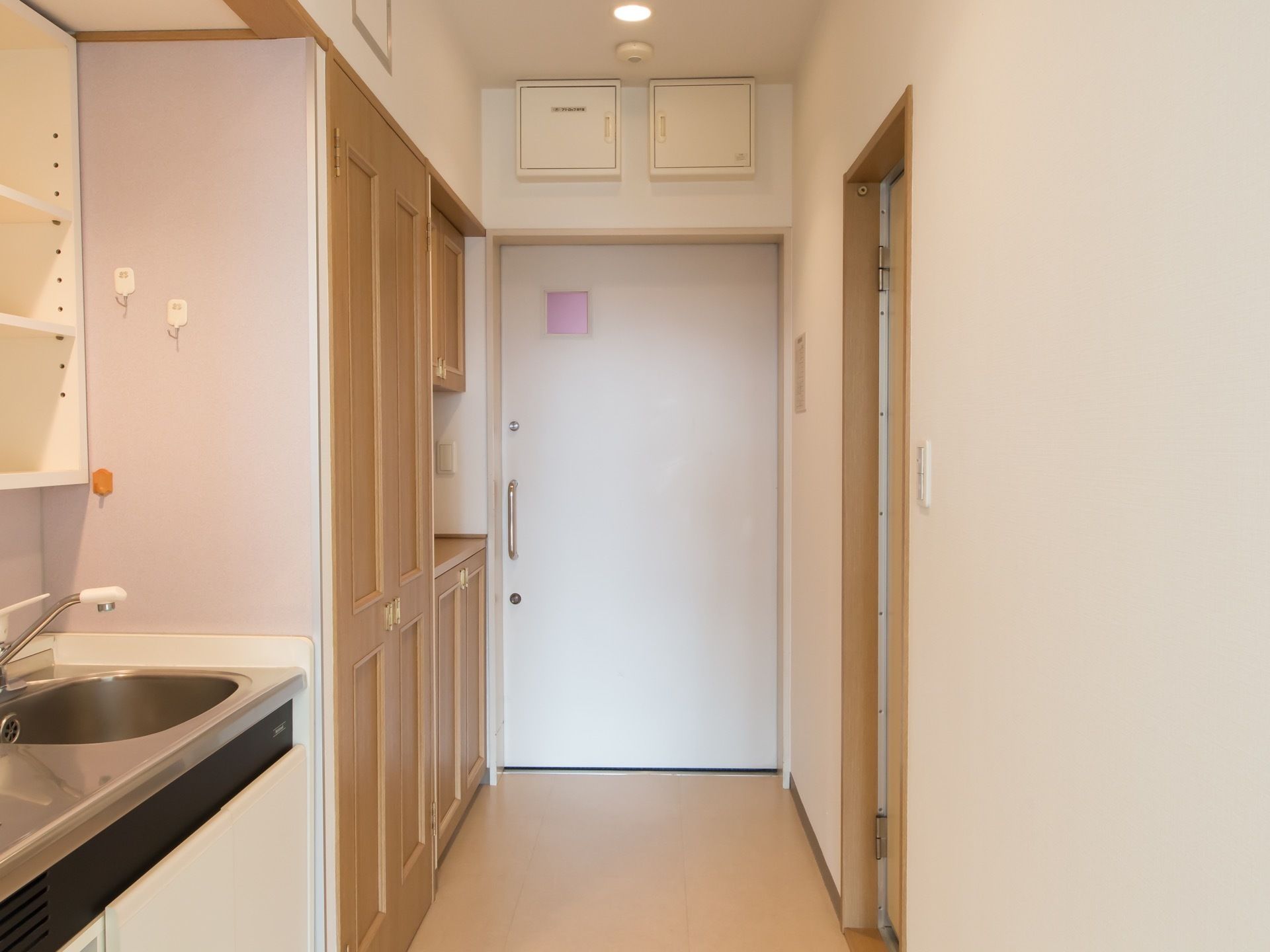 居室の扉は引き戸を取り付けている。扉を入ると横には収納棚が建て付けられている。ミニキッチンも完備されている。