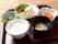 鶏ももの照り焼きがメインの食事は、ご飯とお味噌汁のほか、野菜の和え物、大豆と根菜の炊き合わせが用意され、お盆にのっている。