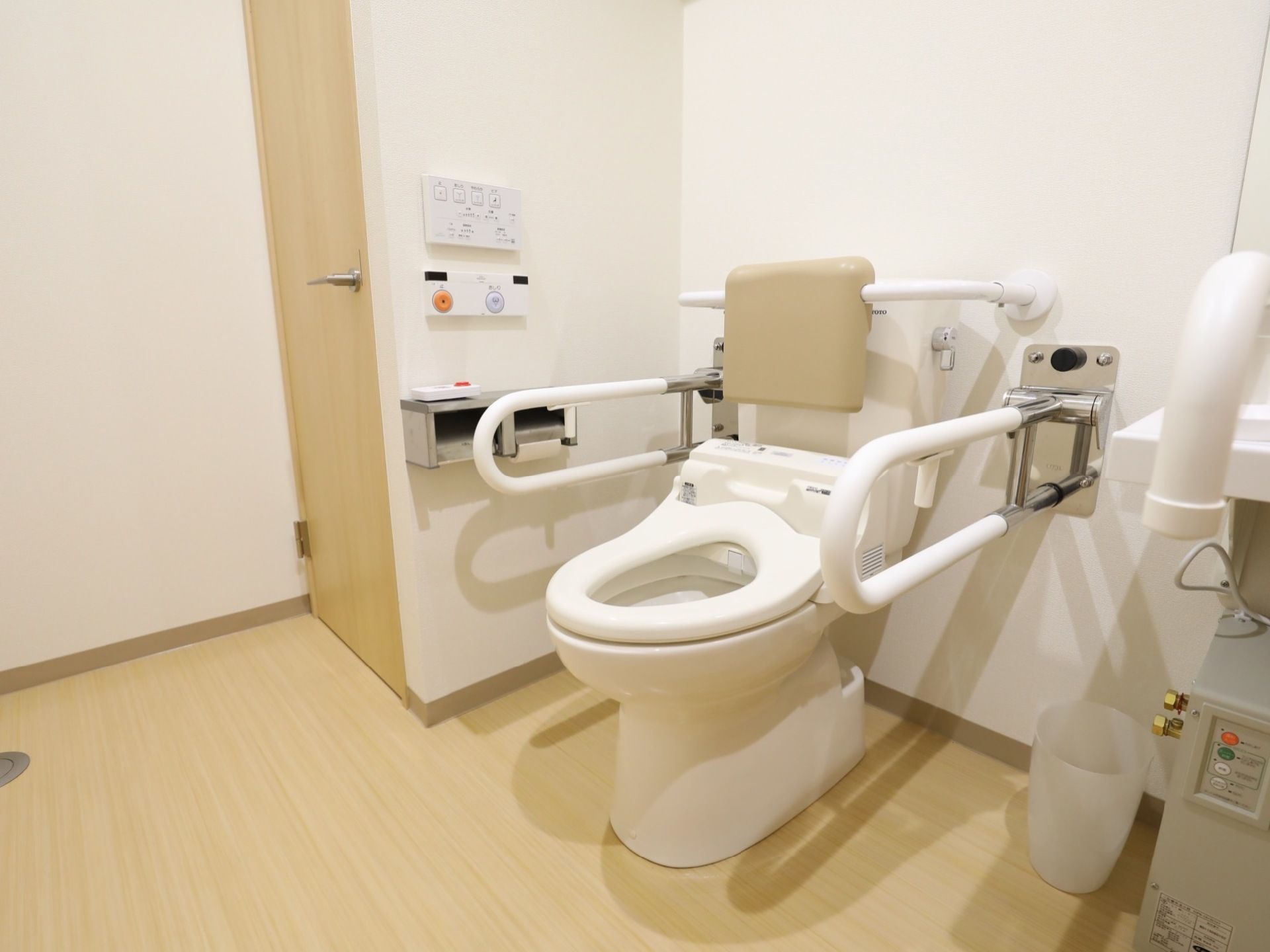 温水洗浄機能付きの便座が完備されている。便座の周りには、クッション付の背もたれや手すりが設置されている。