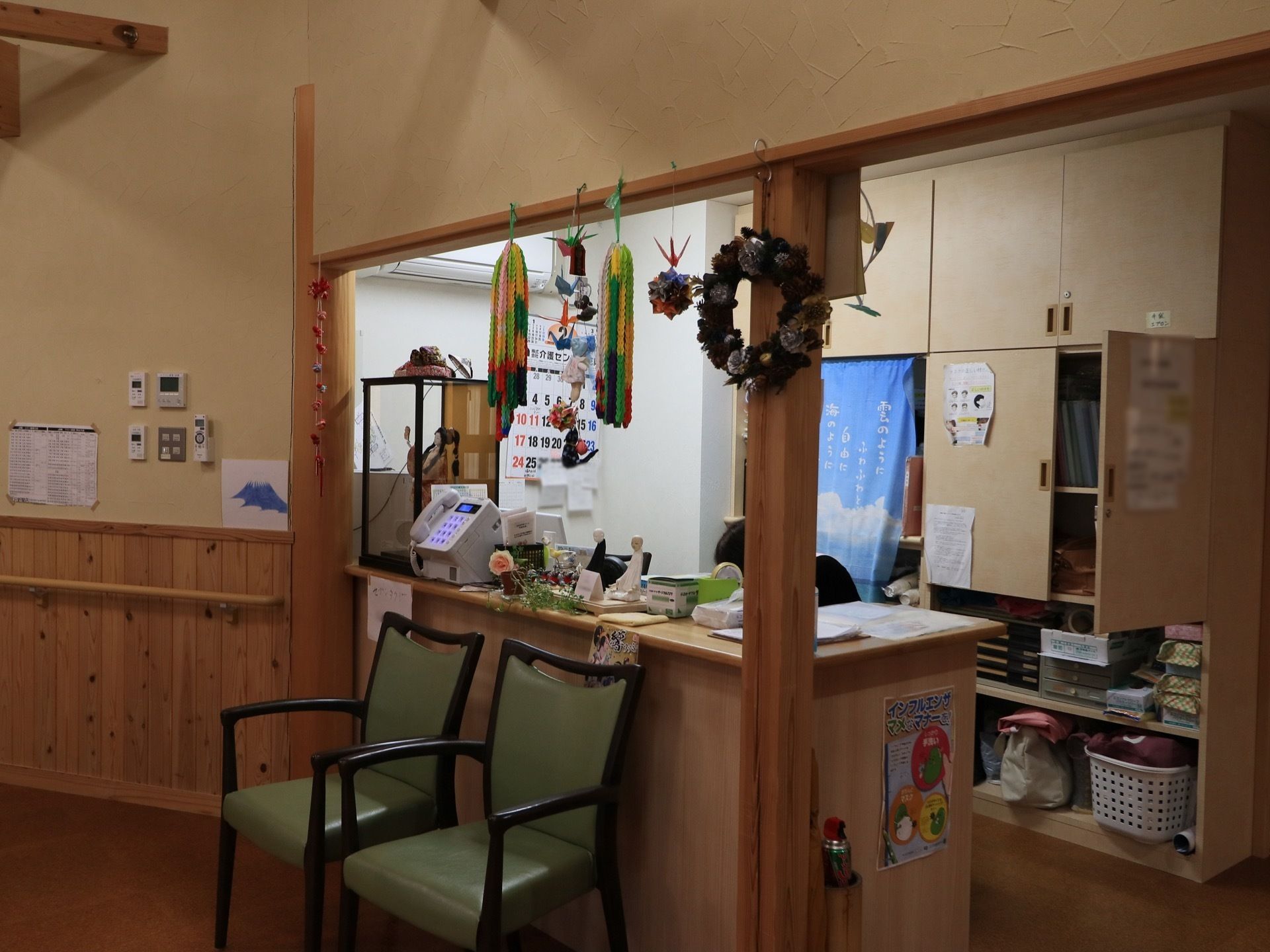温泉宿のような雰囲気の受付になっている。折り紙で折られた鶴や、松ぼっくりで作られたリースが飾られている。