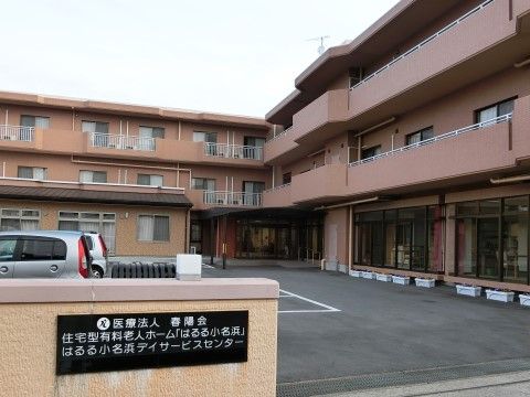 ブラウン系の外壁に親しみが感じられ、手前には駐車場がある施設の外観