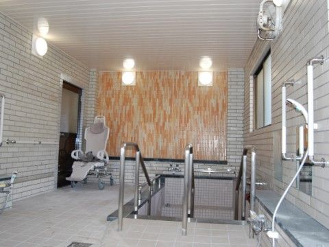 清潔感のあるタイル張りの大浴場である。浴槽に浸かる際に利用する手すりや、非常呼び出しブザーが完備されている。
