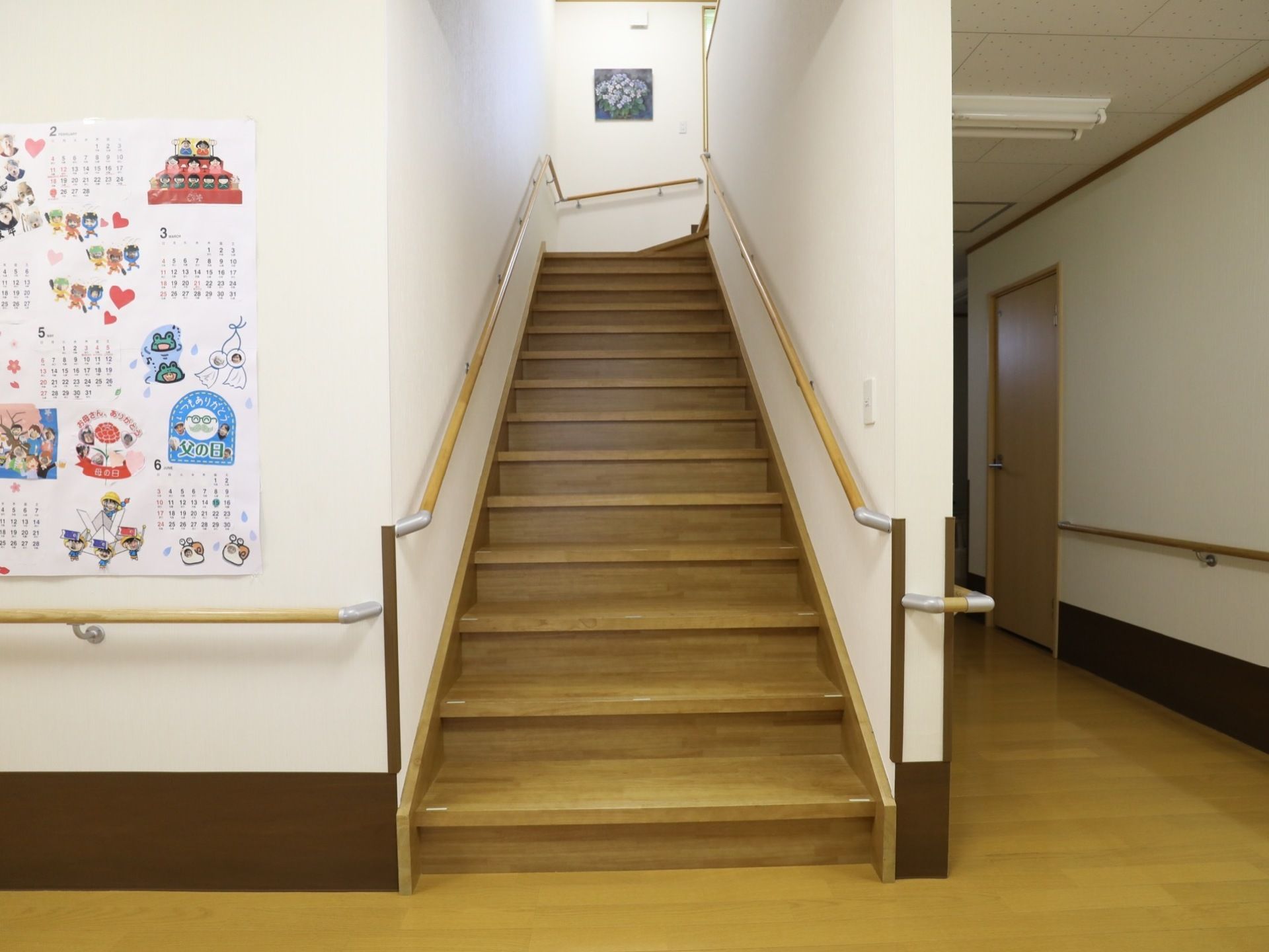 館内に設けられている、1階廊下から2階への階段。階段の幅は広く、両サイドには手すりが取り付けられている。