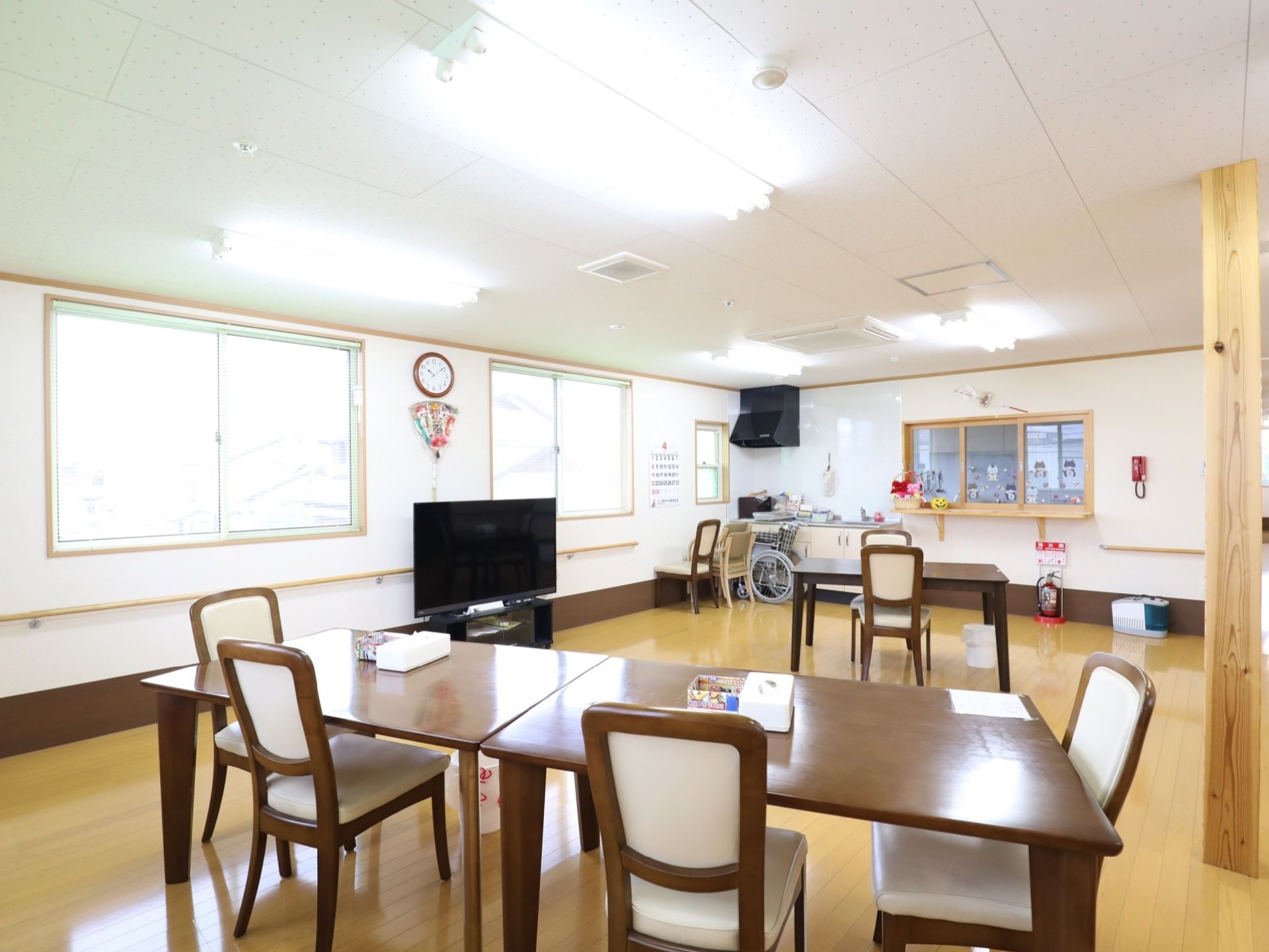 大きな窓に面した明るく広々とした共有スペース。ダイニングテーブルがゆったりとしが間隔で配置されている。