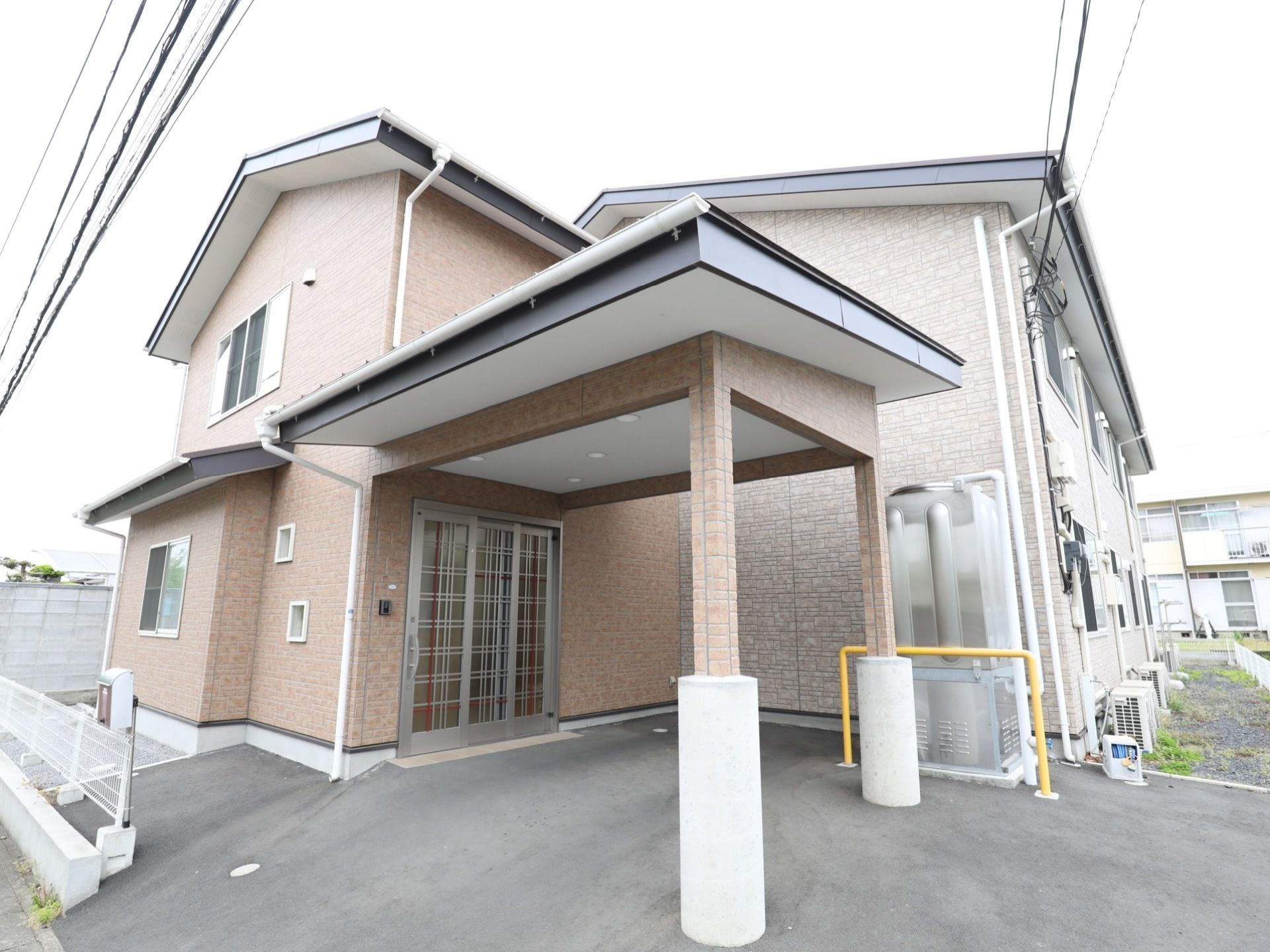 閑静な住宅地に立地している施設の外観。ブラウンのレンガ調の外壁が落ち着いた雰囲気になっている。玄関も前はなだらかな坂になっている。