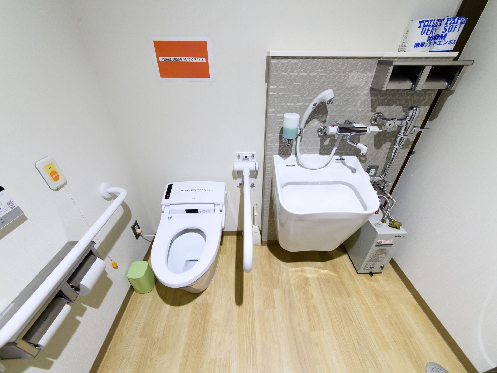 トイレの両側には、頑丈な手すりが取り付けられている。左側の壁にはペーパーホルダーが二つあり、その上に呼出ボタンがある。