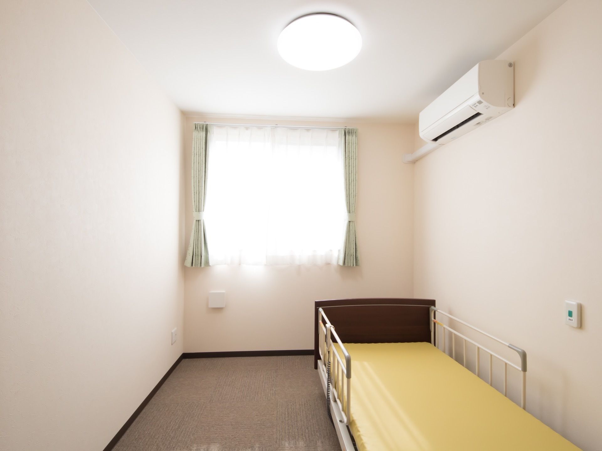 大きな照明や窓がある明るい居室には、転落防止用の柵付きベッドがあり、呼び出しボタンもあるため高齢者も安心。空調完備で快適に過ごせる。