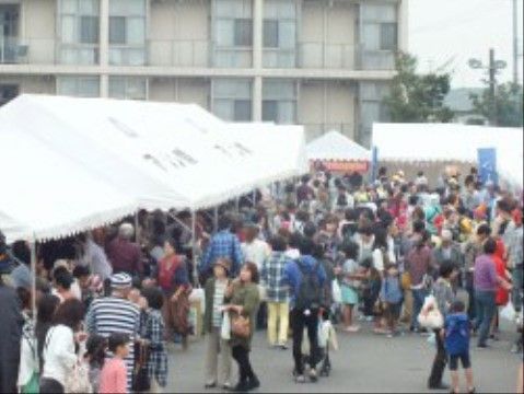 地域のイベントで、会場のテント周辺に集まる人々の様子