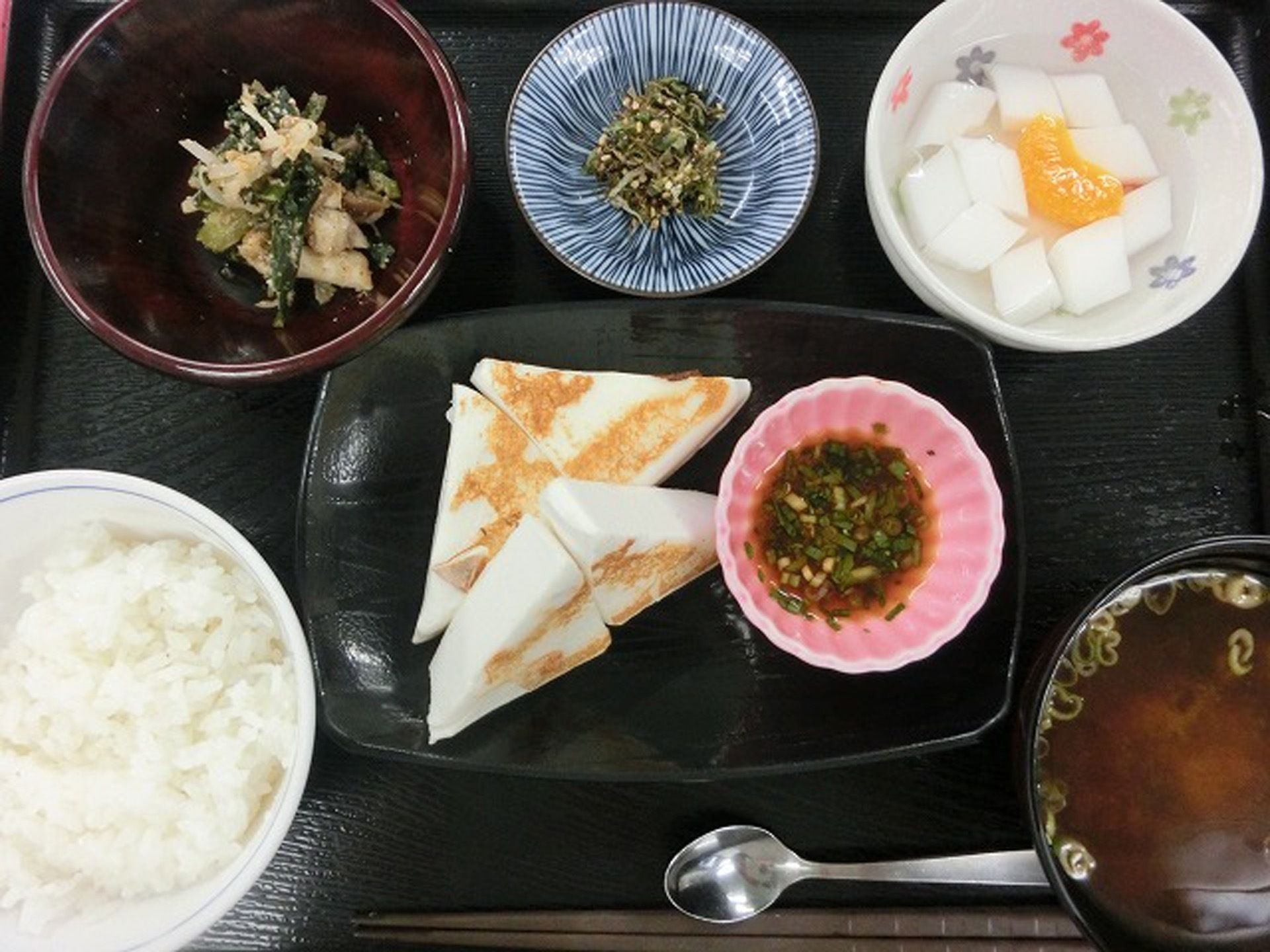 ご飯と汁物、メインおかずに小鉢が３品の食事である。お箸とスプーンを添えている。栄養バランスのとれた献立である。
