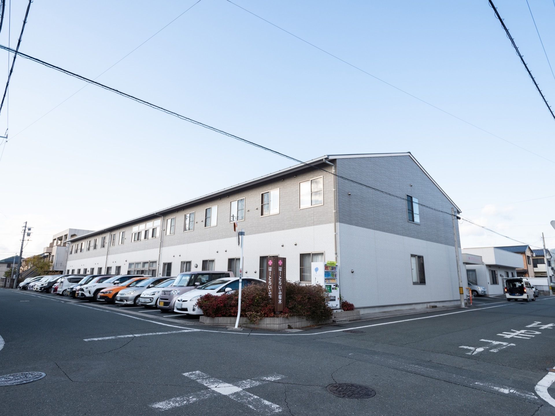 白とライトグレーで統一された２階建ての建物である。周辺には駐車スペースがあり、10台ほど停めることができる。