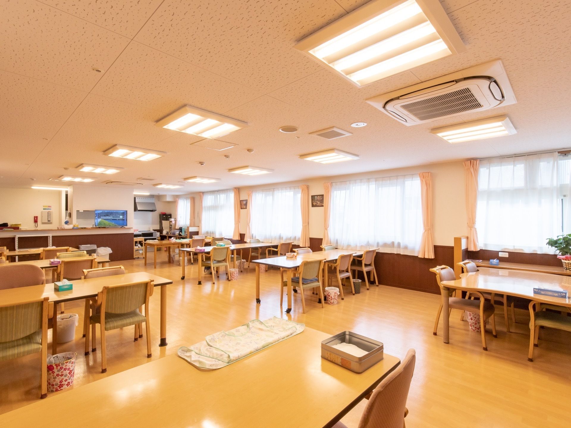 広い食堂はフローリングで、テーブルや椅子がたくさん並べられている。奥には、キッチンとカウンターも設置されている。
