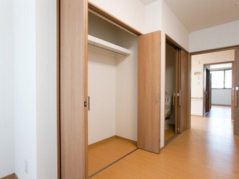 長い通路の脇に折れ戸のついたクローゼットとトイレがある。トイレの入り口はスライドドアになっていて、通路の突き当りには腰高窓がある。