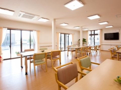 複数の大きな窓から光が差す、明るく広々とした空間である。２本の細い柱の周りにダイニングテーブルと椅子が数脚配置されている。