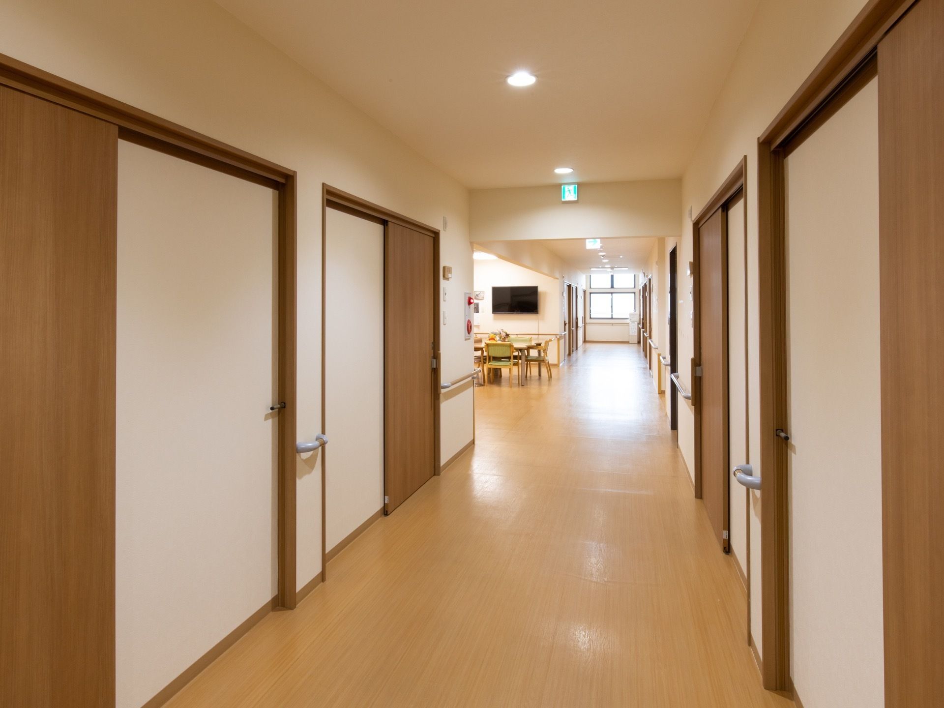通路の両側には手すりが取りつけられ、左手に食堂が配置されている。居室のドアはスライド式になっている。