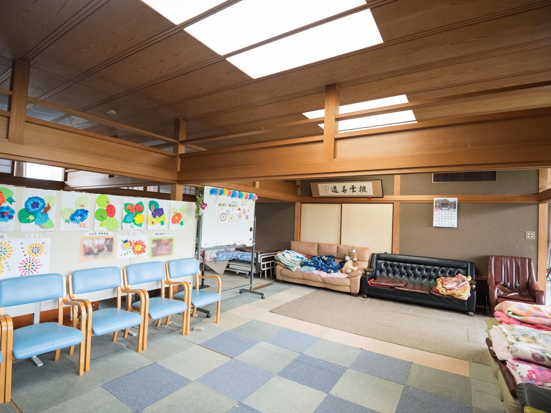 日本家屋のようなリビングで、押入れや欄間がある。床には、フロアクッションが敷き詰められている。壁や押入れの前には、ソファーが置いてある。