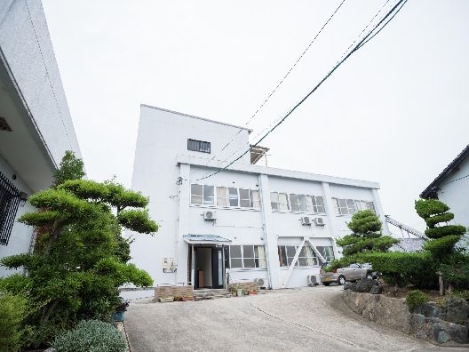 白を基調とした２階建ての建物の玄関先には屋根が付いていて、幅の広いアプローチが続いている。