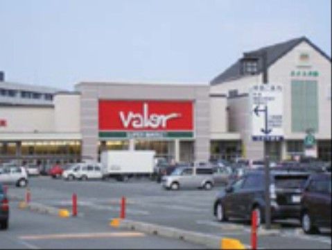 ショッピングモールの建物の外観である。入口の上には大きく店名が表示されており、店舗の前は広い駐車場になっている。