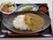 トレーにはカレーライス、野菜サラダ、メロンなどが並べられている。栄養バランスの取れた食事内容になっている。