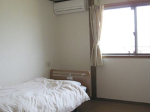 室内にはベッドが置かれており、枕元の壁にナースコールが設置されている。腰高窓があり、カーテンがかかっている。エアコンも備わっている。