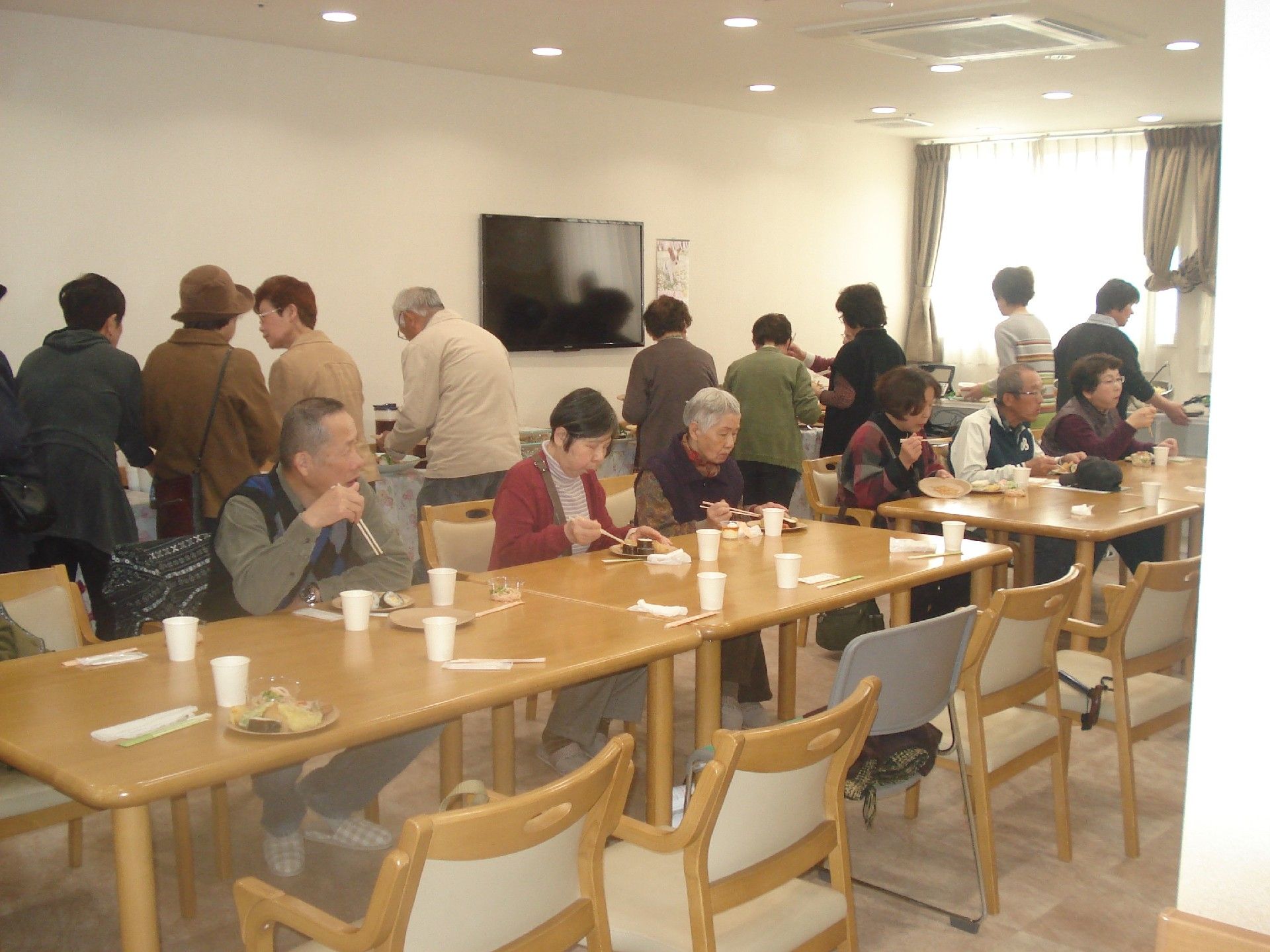 「サービス付き高齢者住宅　サン・セジュールつばき」の地域交流会。地域の方々とお食事を楽しむ様子。