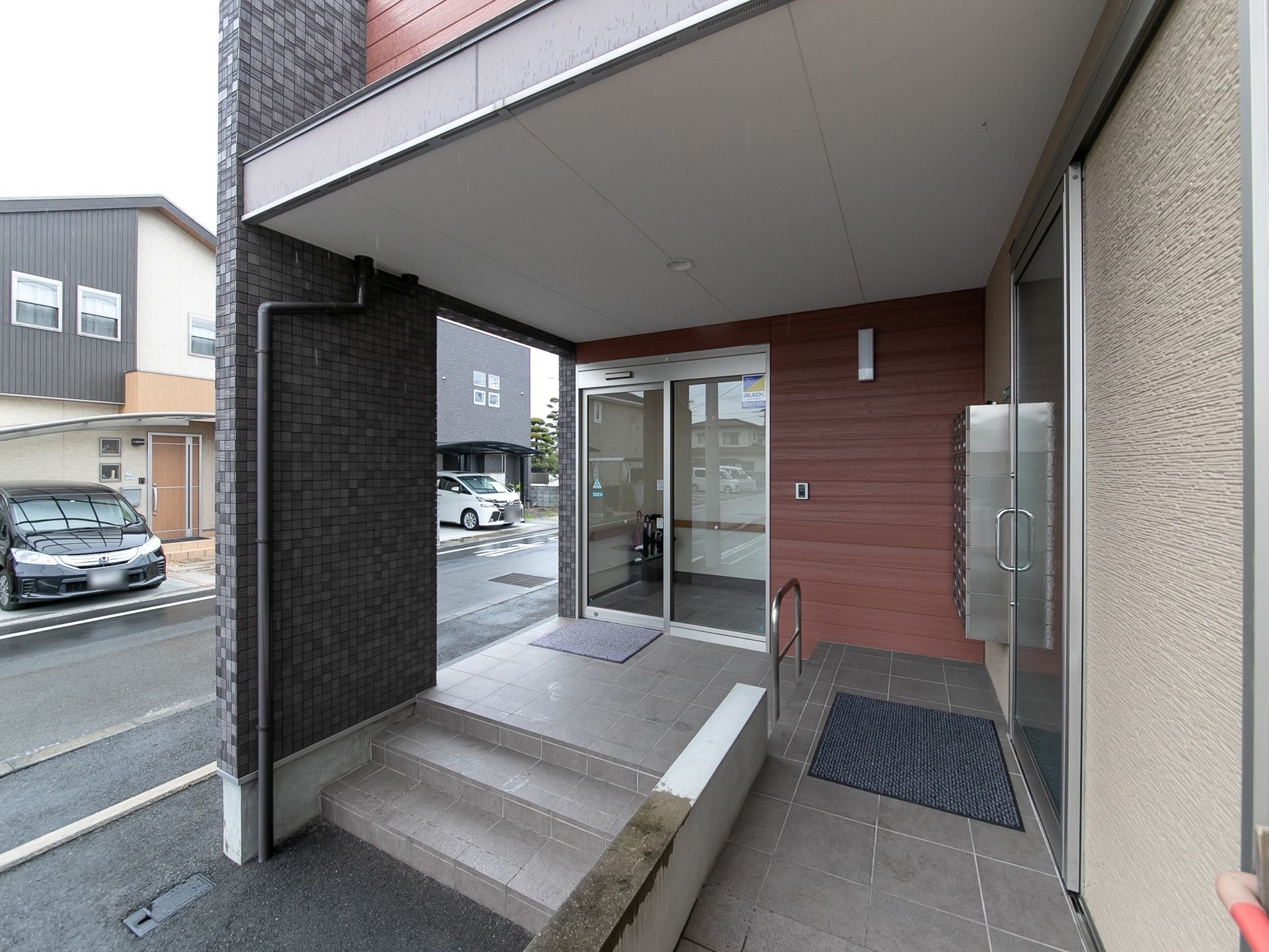 階段とスロープに分かれており、段差を上がったところに手すりがある。玄関の外側に、郵便受けが設置されている。