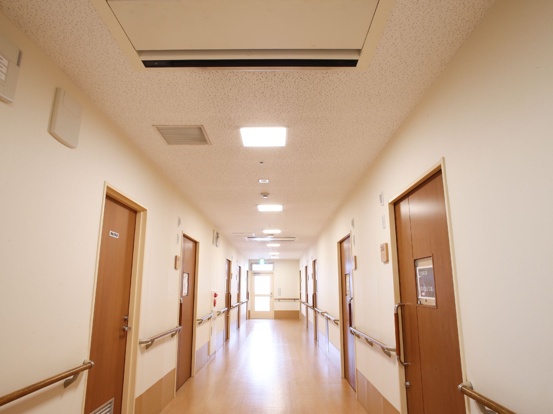 廊下には手すりが並んでいる。また居室はどちらのサイドにも並び、中央の窓には紙がをはっているところがある。