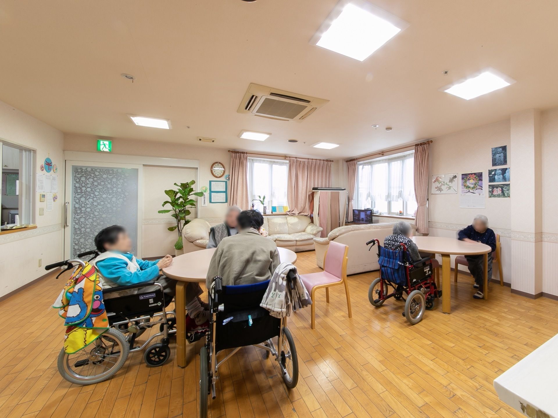 共有スペースに入居者様が集まっている。大きな窓が二面にあって、照明も多くあり、明るいスペースになっている。