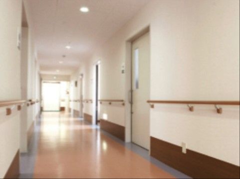 廊下がまっすぐ伸びている。突き当たりに大きな窓があり、日が差し込んで明るい。壁には居室の入口が並んでいる。