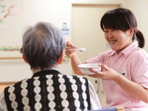 ご入居様に笑顔で食事のサポートをしている女性のスタッフ