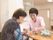 机を挟んで向き合う入居者様とスタッフ。入居者様おひとりおひとりを尊重した、丁寧で細やかなサポートを行う。