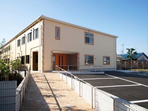 手すりが完備されたスロープがエントランスまで続いている、屋根付きのポーチがある建物