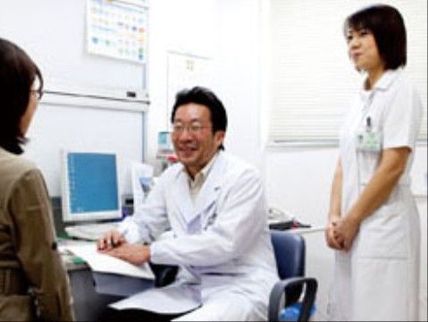 診察室内で、ご入居様に笑顔で対応している医師と看護師