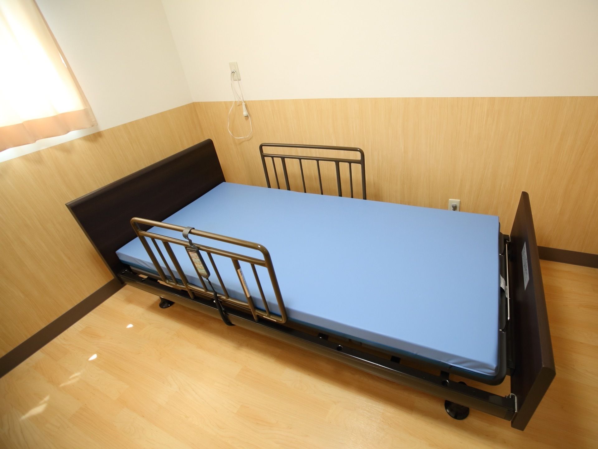 居室にベッドが設置されている。転落防止柵が取り付けられており、安心して夜も眠ることができる。リクライニングなどができるリモコンがある。