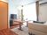 部屋には大きな窓があり、明るい光が差し込んでいる。白い壁の前には、大型テレビが置かれている。その横にテーブルやソファーがある。