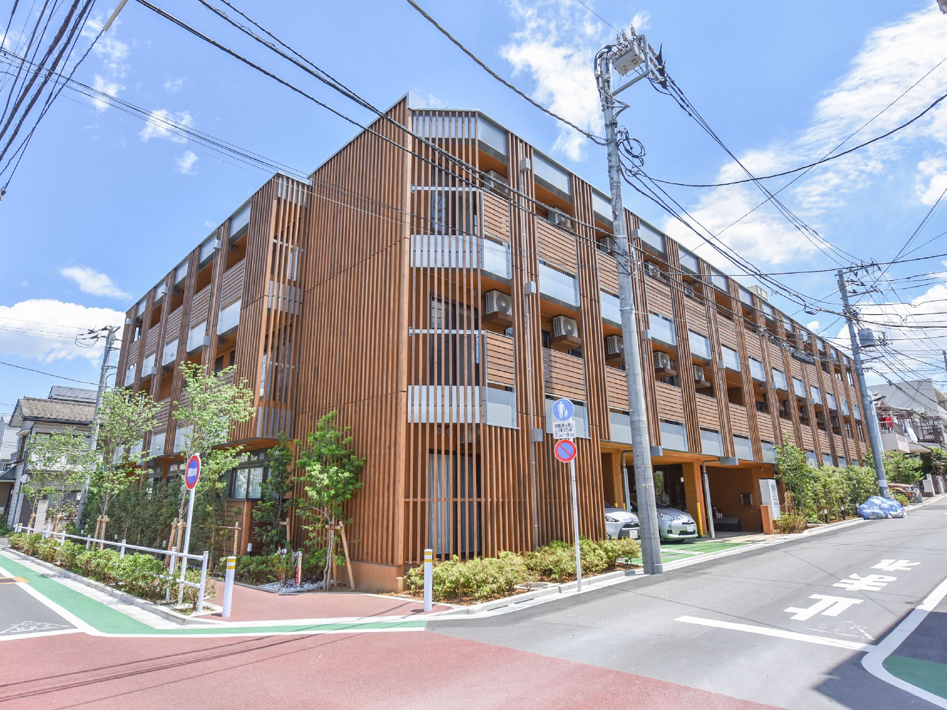 施設は、ストライプの木材で壁面が覆われている。歩道がすぐそばにあり、歩道と道路の境界線には、街路樹が植栽してある。